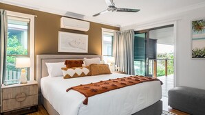 A bedroom with a bed, bedside tables, a ceiling fan, and a view of the outdoors. - Mulivista - spacious home with ocean views & pool (Suffolk Park)