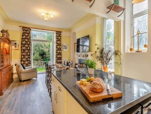 A kitchen with a large island, wooden cabinets, and a view of the outdoors. - The Woodlands House Estate (Berrynarbor)