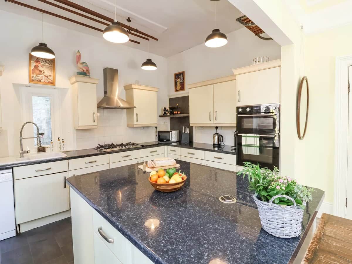 A modern kitchen with white cabinets, a granite countertop, and stainless steel appliances.