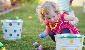 A child playing with Easter eggs on grass.