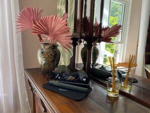 A wooden dresser with decorative items including vases, a mirror, and a black electronic device.
