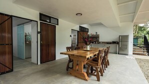 A spacious kitchen with a dining area, featuring a wooden table and chairs, a refrigerator, and a kitchen counter. - Spacious 3BR Villa Just 5 Min Walk to the Beach | Master Suite & Saltwater Pool (Puerto Viejo de Talamanca)