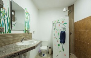 Une salle de bain avec un lavabo en granit, des toilettes blanches et une douche, avec une serviette accrochée au mur.
