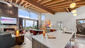 A spacious living area with a large island, a fireplace, and a view of the outdoors.