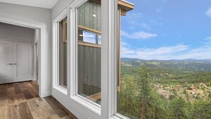A room with large windows offering a view of a forested landscape.