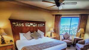 A hotel room with a large bed, a ceiling fan, a view of the city, and a seating area with a chair and a table. - Experience Tahoe's Ski Scene at Holiday Inn Club Vacations Tahoe Ridge Resort (Stateline)