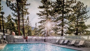 A swimming pool with lounge chairs, surrounded by trees and a stone wall. - Experience Tahoe's Ski Scene at Holiday Inn Club Vacations Tahoe Ridge Resort (Stateline)
