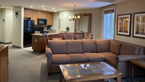 A modern living room with a brown sectional sofa, a glass coffee table, and a dining area with patterned chairs. - Experience Tahoe's Ski Scene at Holiday Inn Club Vacations Tahoe Ridge Resort (Stateline)