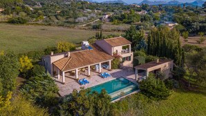 Una villa con piscina, zona de estar exterior y vistas al campo circundante.
