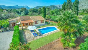 Una casa con piscina, rodeada de exuberante vegetación y montañas al fondo.