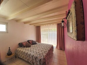 Une chambre à coucher avec un lit, une petite table, une fenêtre et un rideau.