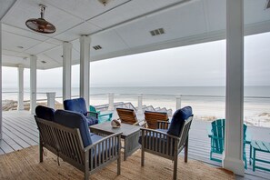 Un espace extérieur abrité, aménagé avec du mobilier en bois et offrant une vue sur la plage.
