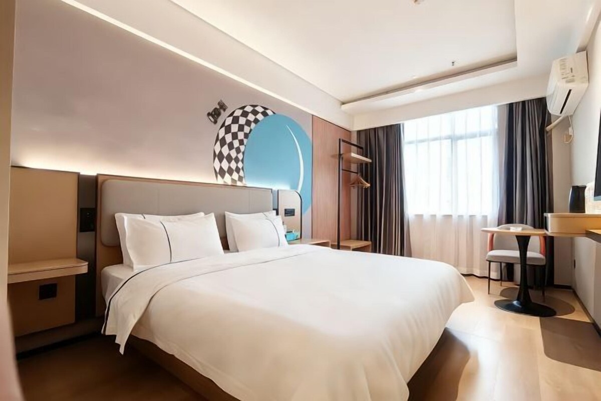 Una habitación de hotel con una cama grande, mesitas de noche, un escritorio y una silla.