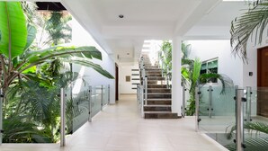A modern interior with a glass railing, a staircase, and lush greenery. - Beachfront Condo w/ Large Balcony and Ocean Views near Downtown Playa Del Carmen (Playa del Carmen)