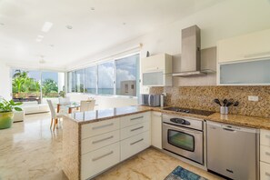 A modern kitchen with a large island, stainless steel appliances, and a view to the outdoors.