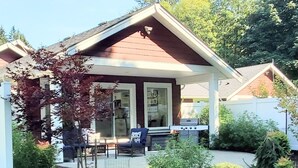 A house with a covered patio, a grill, and a small garden. - A modern cozy cottage in your own wooded backyard located mid Vancouver Island. (Qualicum Beach)