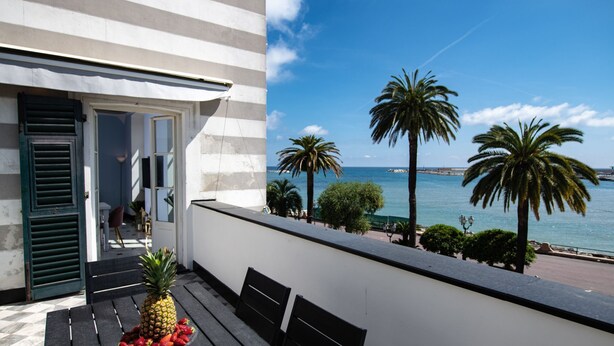 Ein Balkon mit Blick auf das Meer, Palmen und einer Ananas mit Erdbeeren.
