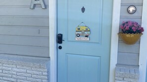 Una puerta azul claro con un letrero de bienvenida, un buzón y una maceta en la pared.