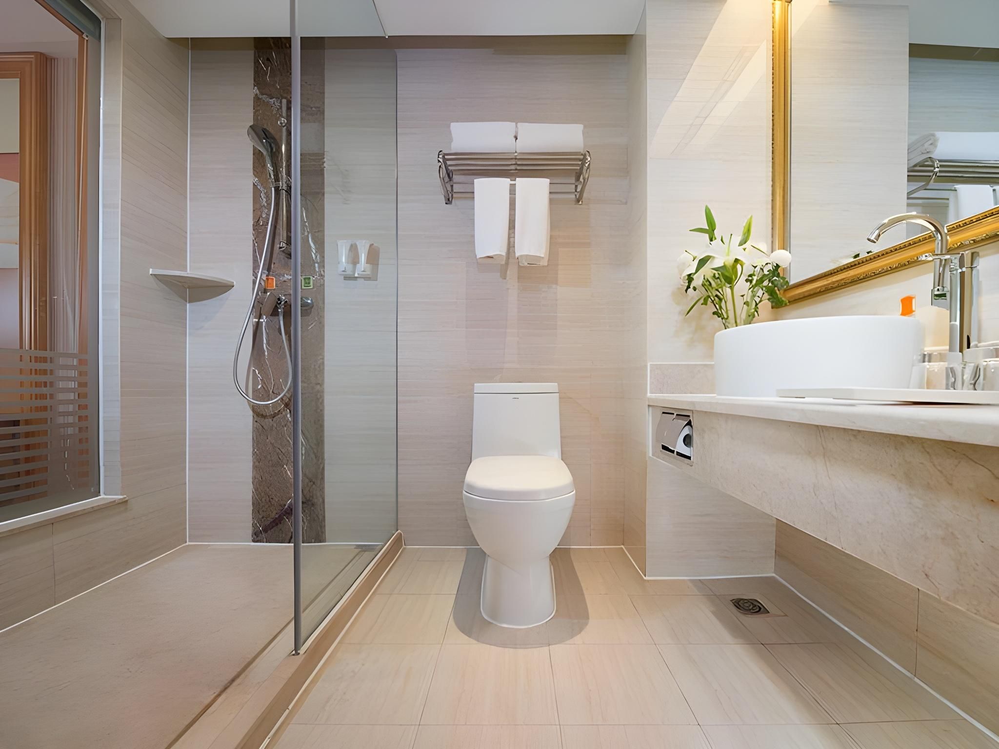 A modern bathroom with a glass-enclosed shower, a toilet, and a sink with a mirror.