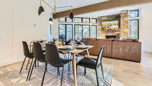 Une cuisine moderne avec un coin repas, une cheminée en pierre et de grandes fenêtres.