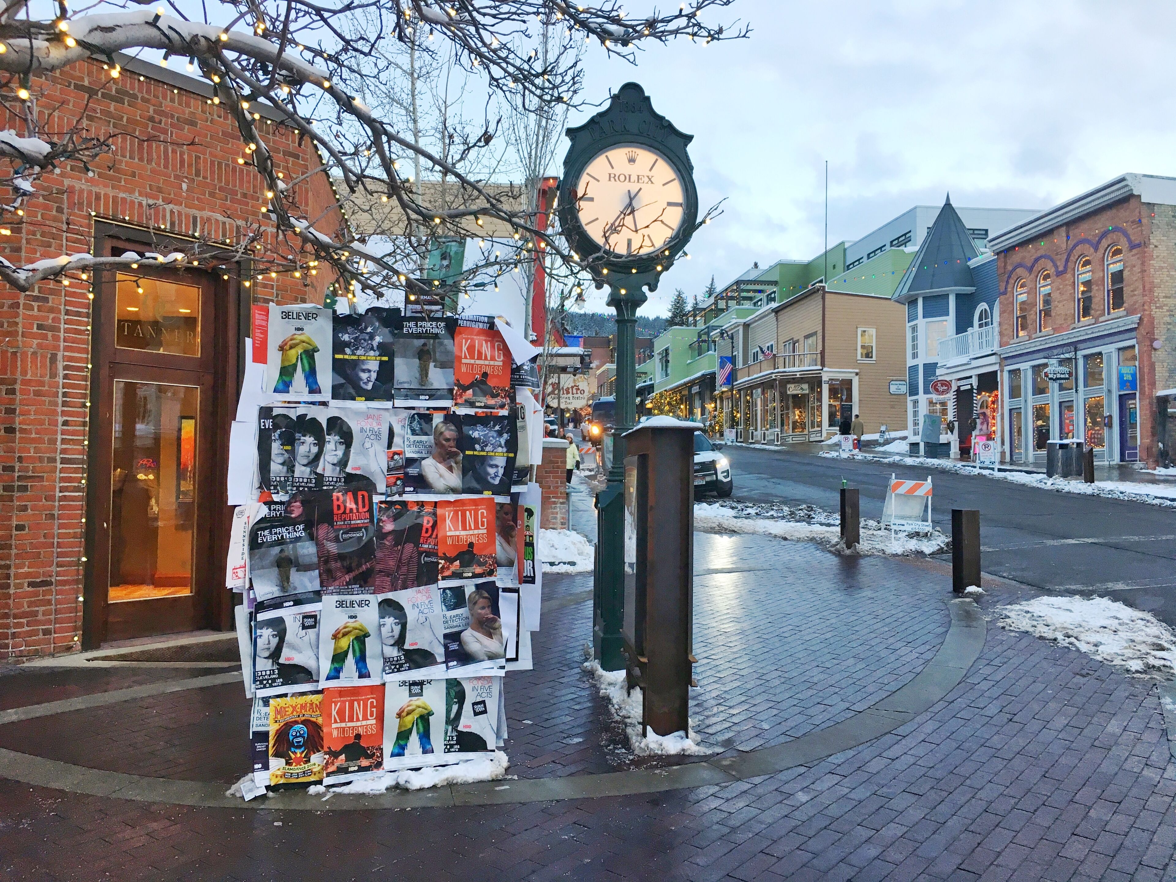 Une devanture de magasin avec une horloge Rolex, une collection d’affiches de films et un bâtiment en briques.