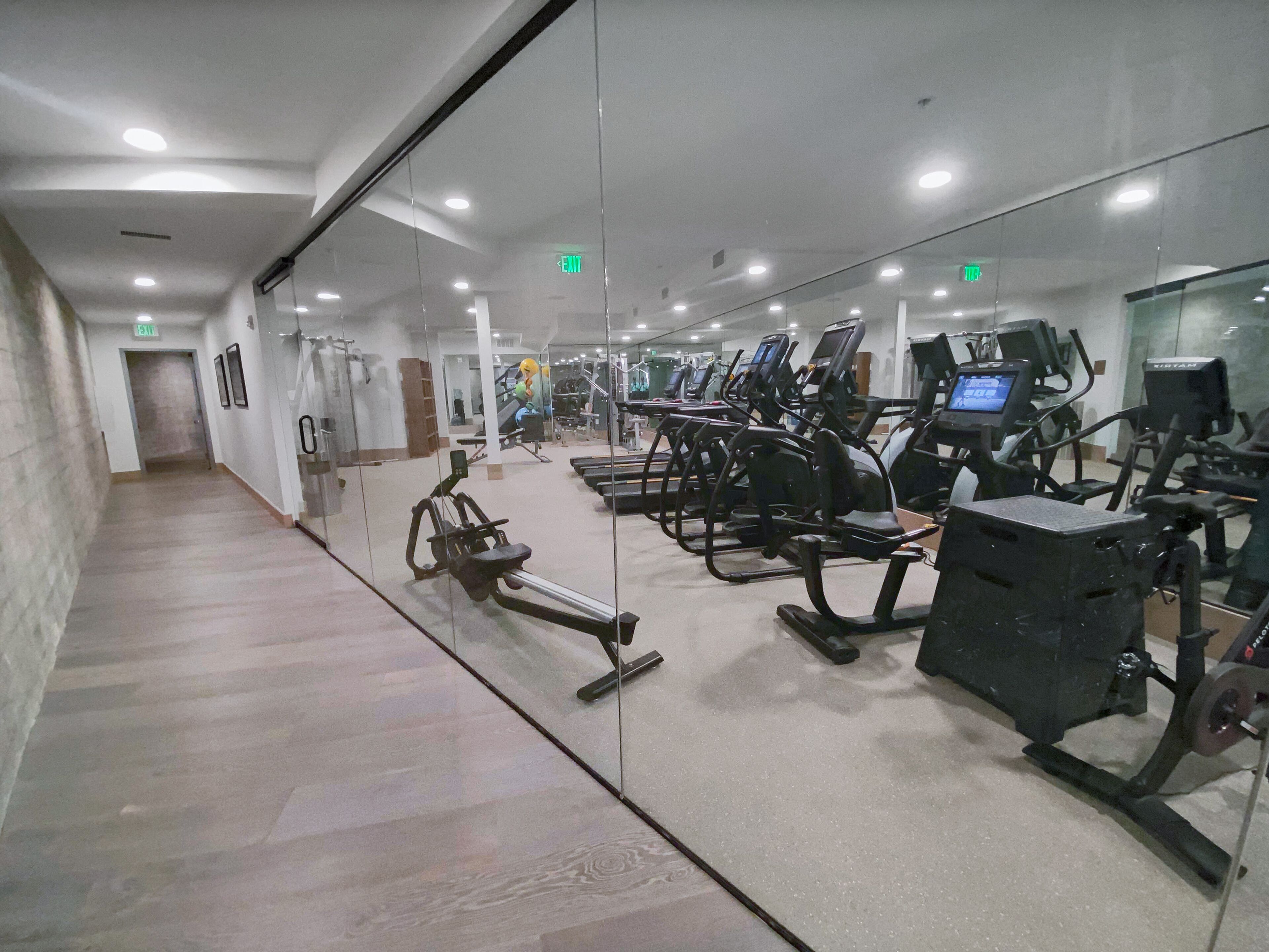 Une salle de sport équipée de machines de cardio, de machines de musculation et d’un mur recouvert de miroirs.