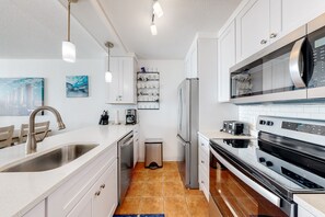 Enjoy cooking in this well-equipped kitchen with an oven, microwave, and refrigerator, plus a large island with sink and ample counter space.