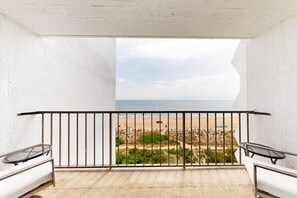 Enjoy the serene beach view from this balcony with a metal railing and comfortable seating areas.