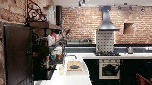 Une cuisine avec un mur en briques, une cuisinière à gaz, une hotte aspirante et un four encastré.