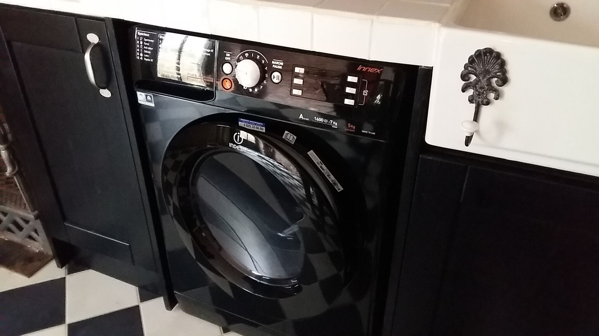 A front-loading washing machine with a digital control panel, a stainless steel handle, and a black exterior.