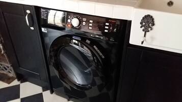A front-loading washing machine with a digital control panel, a stainless steel handle, and a black exterior.