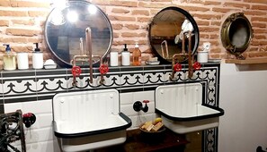 Een badkamer met twee wasbakken, een spiegel en toiletartikelen aan de muur.
