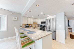 Enjoy cooking in this well-equipped kitchen with a central island, appliances, and a large window.