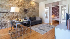 Una sala de estar moderna con una pared de piedra, una mesa de comedor con sillas, un sofá y una chimenea.