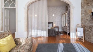 Una habitación con cama, mesita de noche, lámpara y pared de piedra.