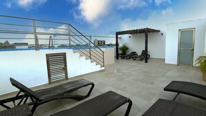 A rooftop terrace with outdoor seating, a pergola, and a staircase leading to an upper level. - Menesse 25.26 (Playa del Carmen)
