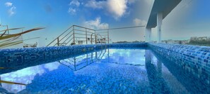 A rooftop swimming pool with a blue mosaic design, surrounded by a metal railing and a clear sky. - Menesse 25.26 (Playa del Carmen)