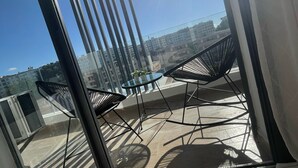 A modern balcony with a glass door, metal railings, and two black chairs. - Cozy and beautiful apartment 2 steps from la corniche (Dar-el-Beida)