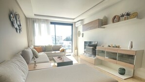 A modern living room with a large bed, a sofa set, a coffee table, and a TV stand. - Cozy and beautiful apartment 2 steps from la corniche (Dar-el-Beida)