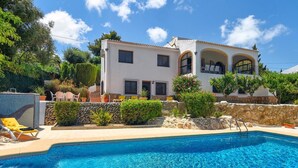 Une maison à deux étages avec une piscine en premier plan.