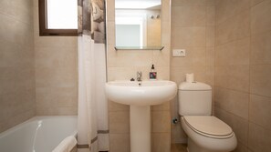 Un baño con lavamanos, inodoro y bañera blancos.