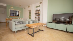 A living room with a sofa, a coffee table, a TV, and a bookshelf.