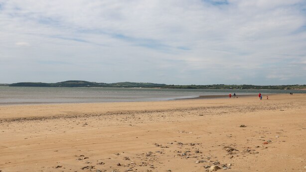 A wide sandy beach with a calm sea and distant hills. - Lane Cottage (Ballycullane)