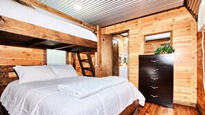 A wooden cabin room with a bunk bed, a dresser, and a mirror.