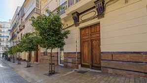 A row of buildings with a tiled sidewalk and a tree in the foreground.