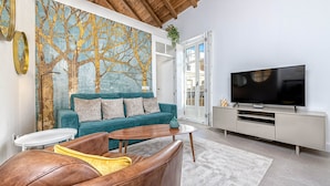 A modern living room with a teal sofa, leather armchair, and a large flat-screen TV.