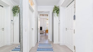 A hallway with white walls, a striped rug, and doors on either side.