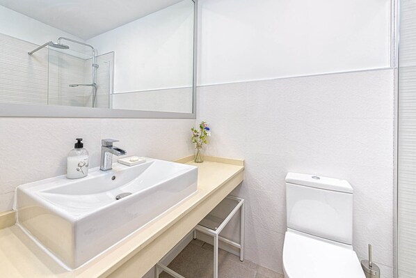 Un baño moderno con un lavamanos grande blanco, un espejo y un inodoro.