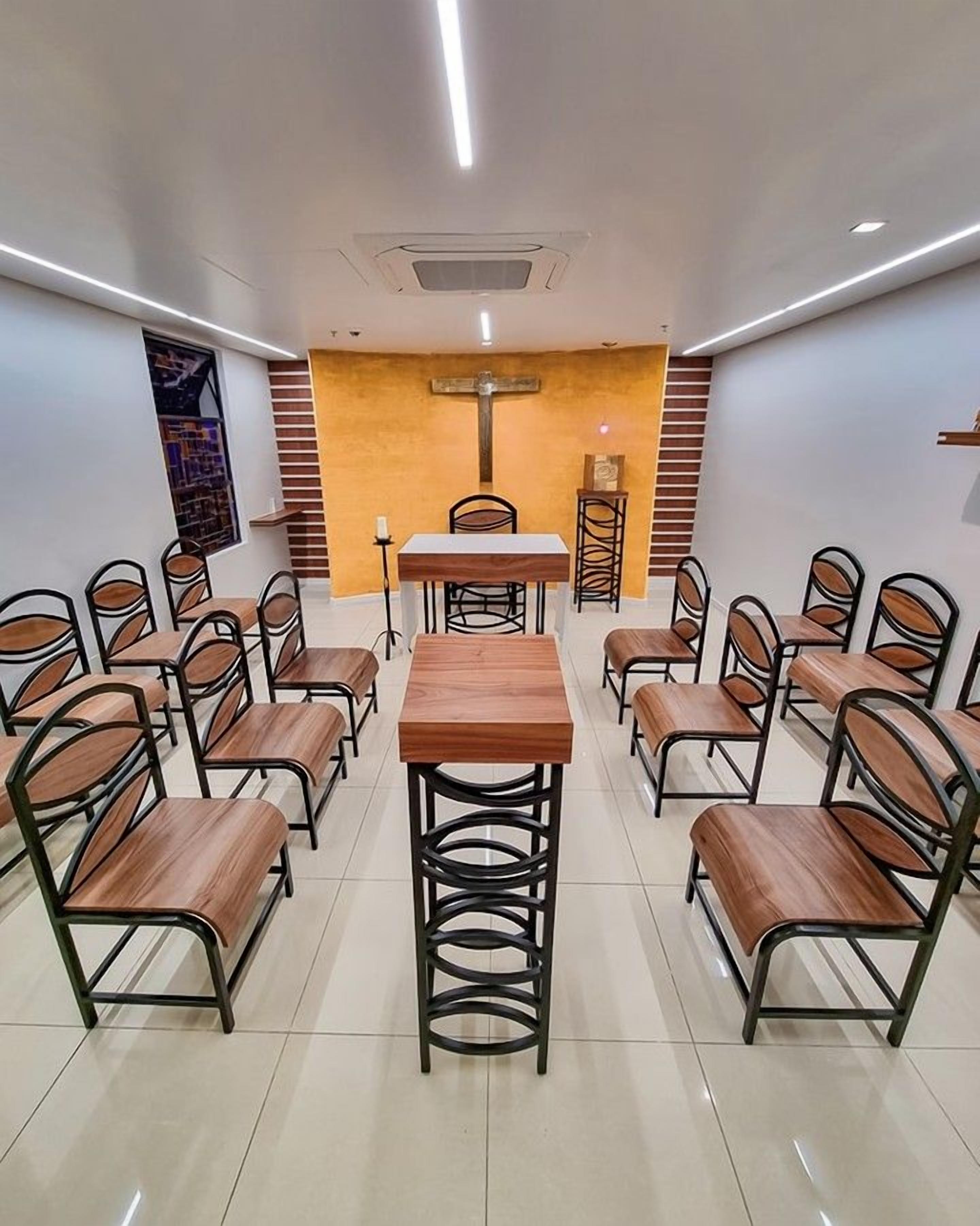 A conference room with a central table, surrounded by chairs, and a cross on the wall.