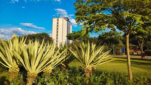 Un edificio de diseño moderno, rodeado de abundante vegetación y un cielo azul despejado.